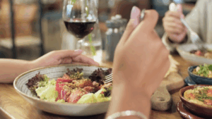 Closeup of Restaurant dining table with people's plates, wine glasses and hands as they eat